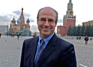 How a Billionaire Con Man Has Been a Key Driver Behind the Barrage of Anti-Russian Propaganda that Could Lead Us Into World War III A person in a suit and tie Description automatically generated