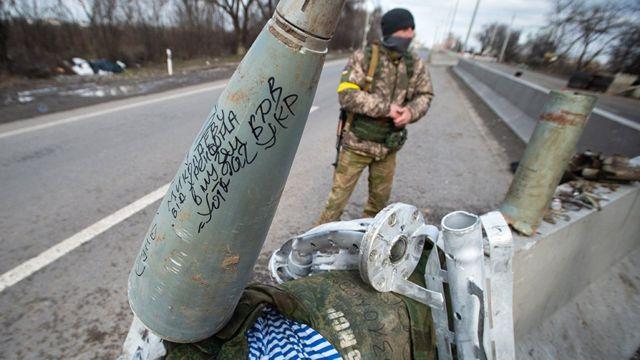 A person in camouflage standing next to a missile

Description automatically generated