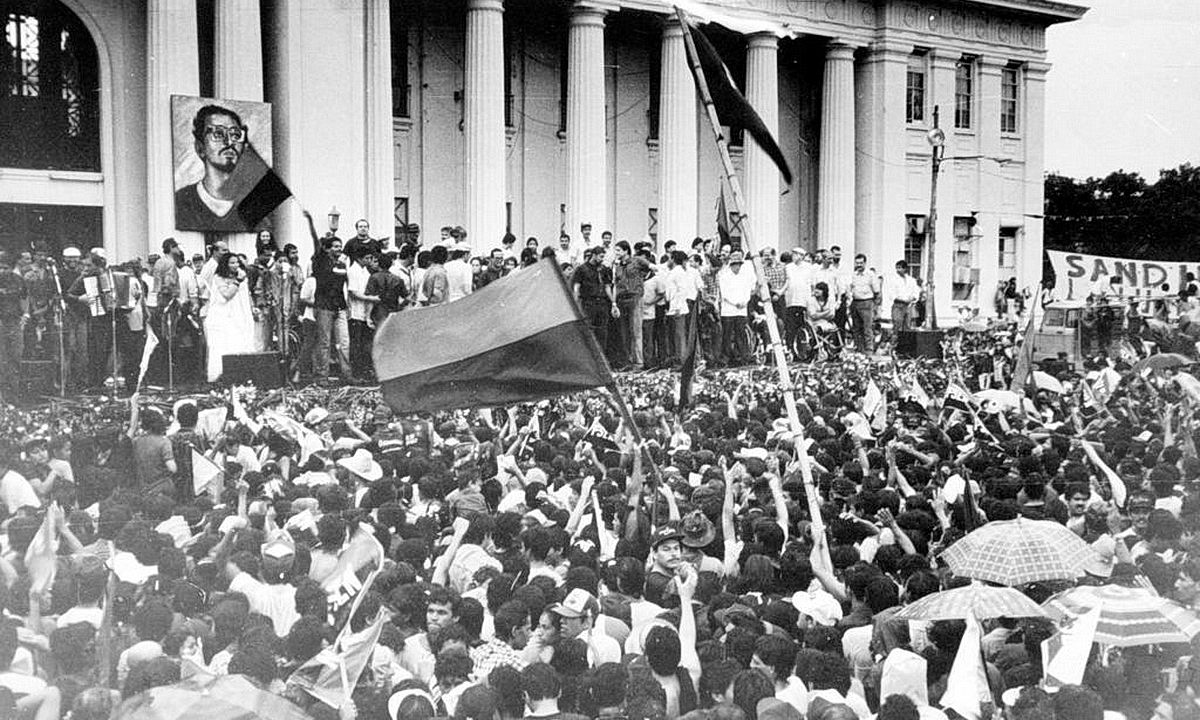 A large crowd of people holding flags

Description automatically generated