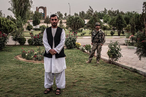 A man in traditional Afghan attire with his hands clasped at his waist
