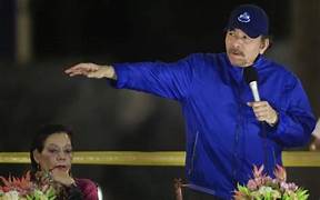 A person in a blue jacket pointing at a microphone

Description automatically generated