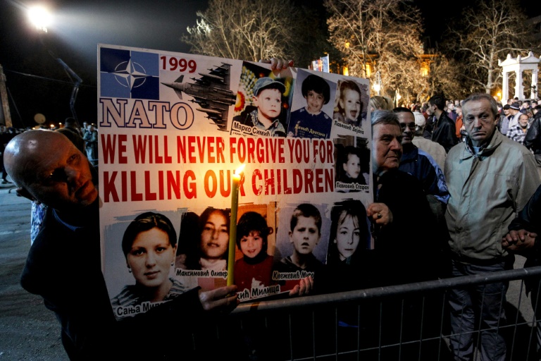 People holding a sign with pictures of children

Description automatically generated