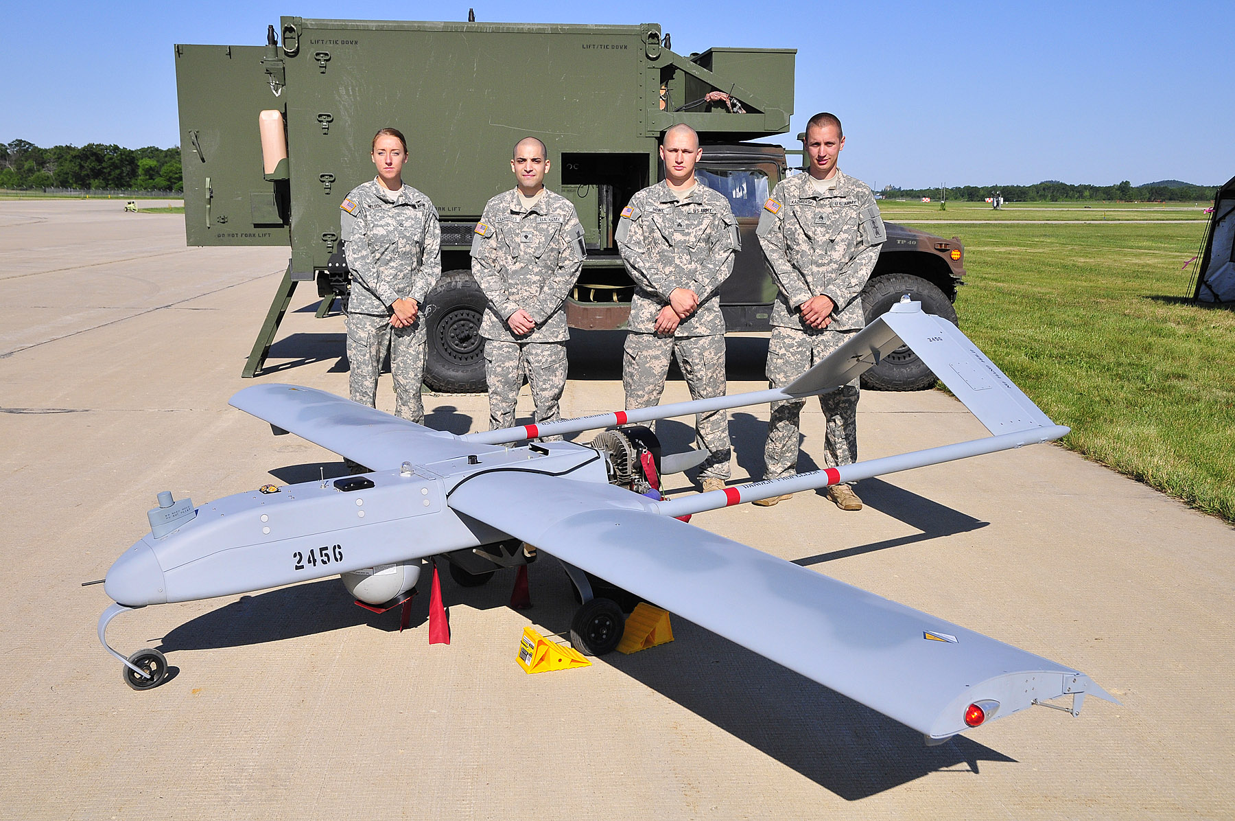A group of soldiers standing next to a drone

Description automatically generated