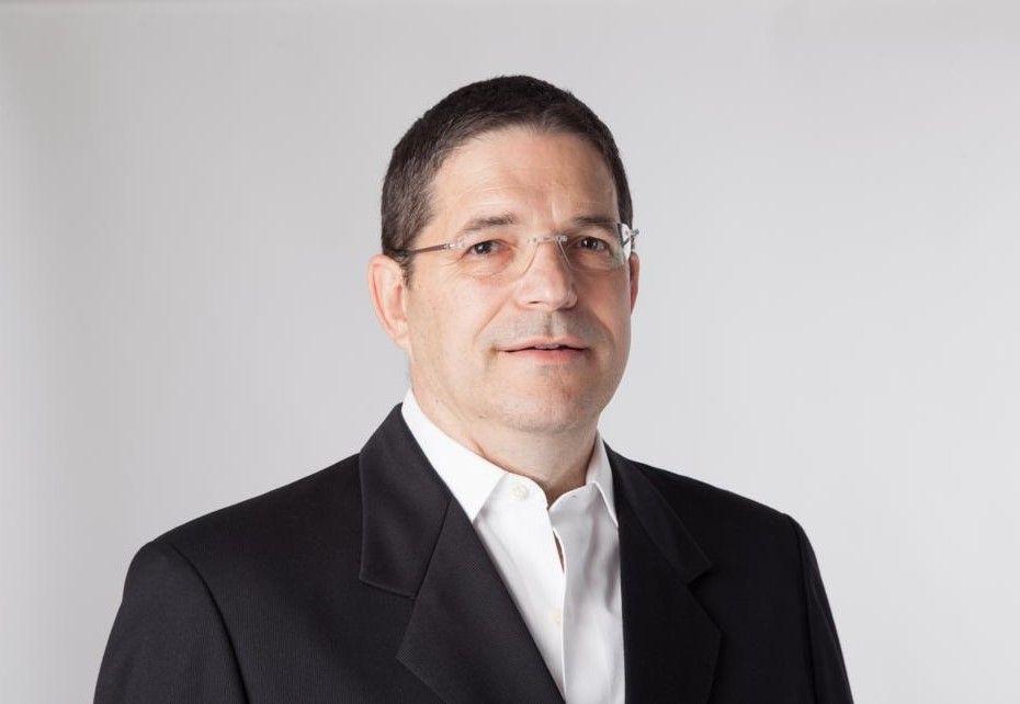 A person in a suit and glasses

Description automatically generated
