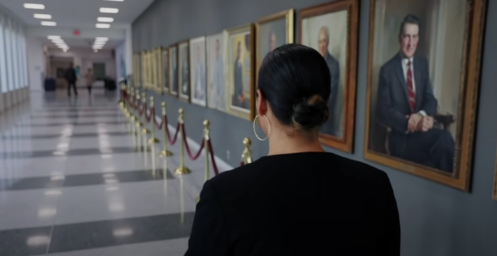 A person looking at a wall of paintings

Description automatically generated
