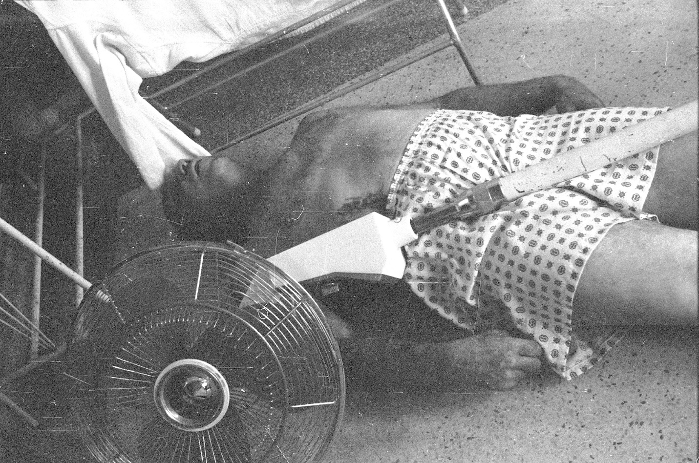 A person lying on the floor with a fan

Description automatically generated