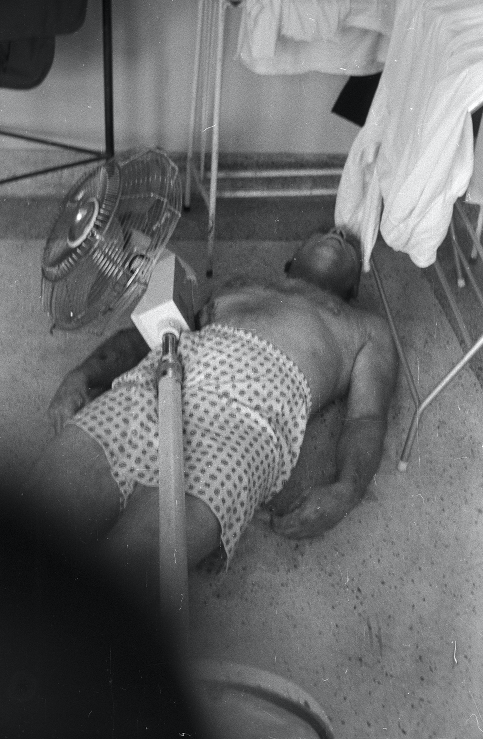 A person lying on the floor with a fan

Description automatically generated