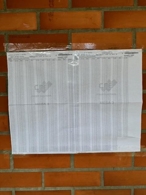 A piece of paper on a brick wall Description automatically generated
