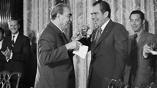 A couple of men in suits toasting with a drink

Description automatically generated