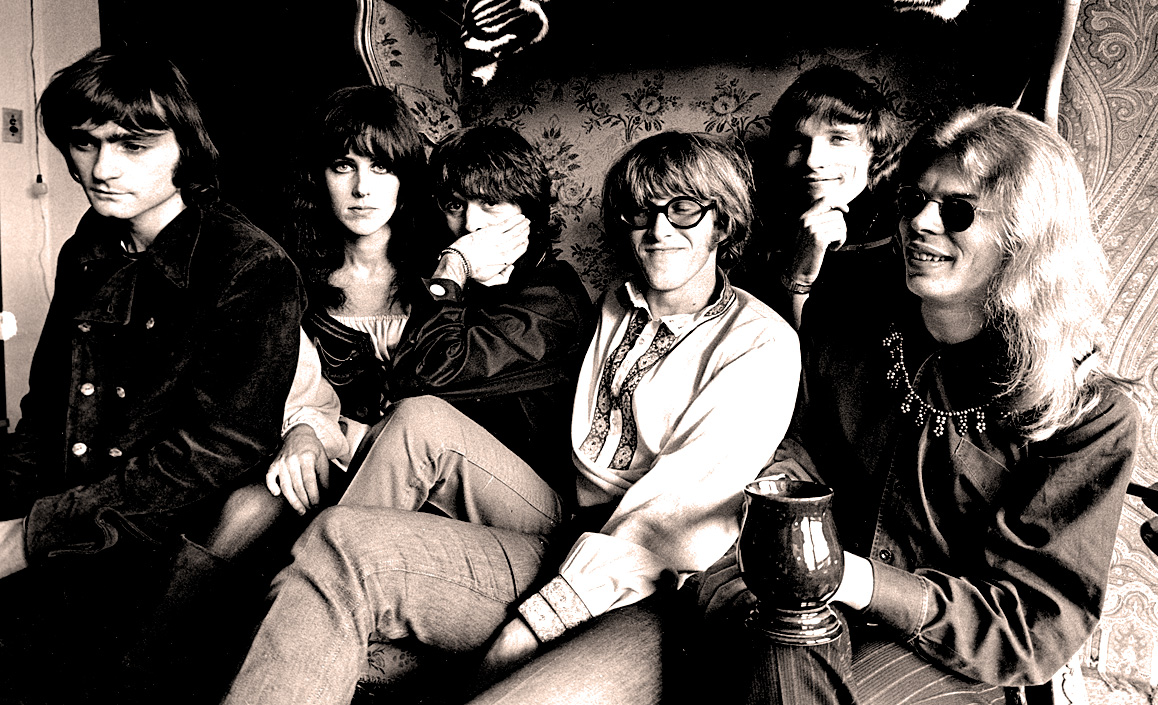 A group of people sitting on a couch with Studio 54 in the background

Description automatically generated