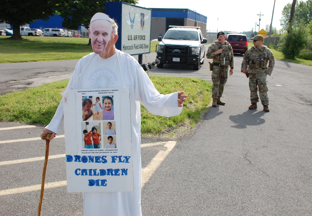 A person in a white robe holding a sign

Description automatically generated