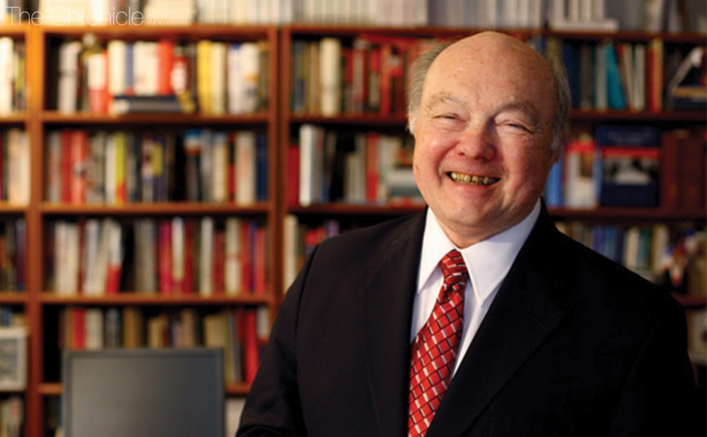 A person smiling in front of a bookshelf

Description automatically generated