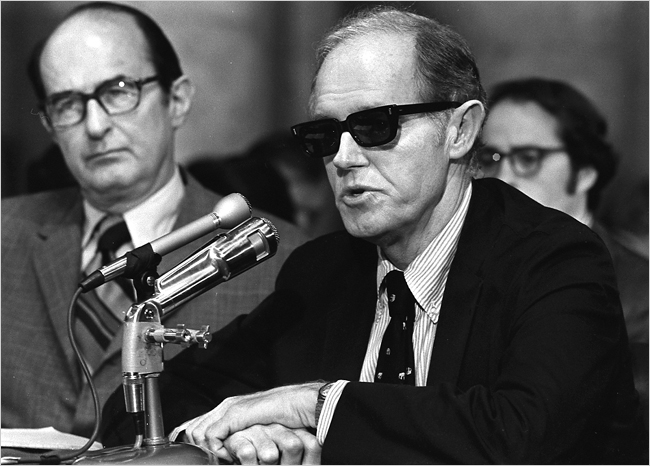 A person wearing sunglasses and a suit and tie

Description automatically generated