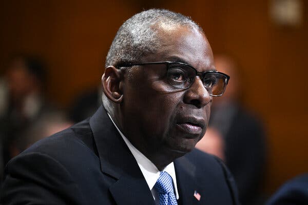 Defense Secretary Lloyd J. Austin III, wearing a dark suit and blue tie.