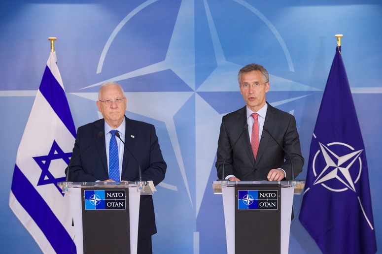 Men standing at podiums with flags

Description automatically generated
