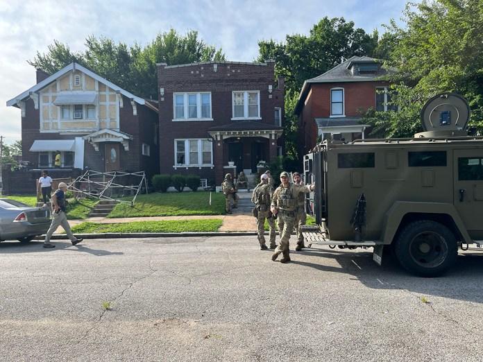 A group of people in uniform standing in front of a house Description automatically generated