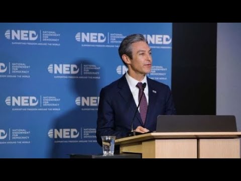 A person in a suit at a podium
Description automatically generated
