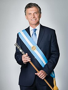 A person in a suit holding a baton

Description automatically generated
