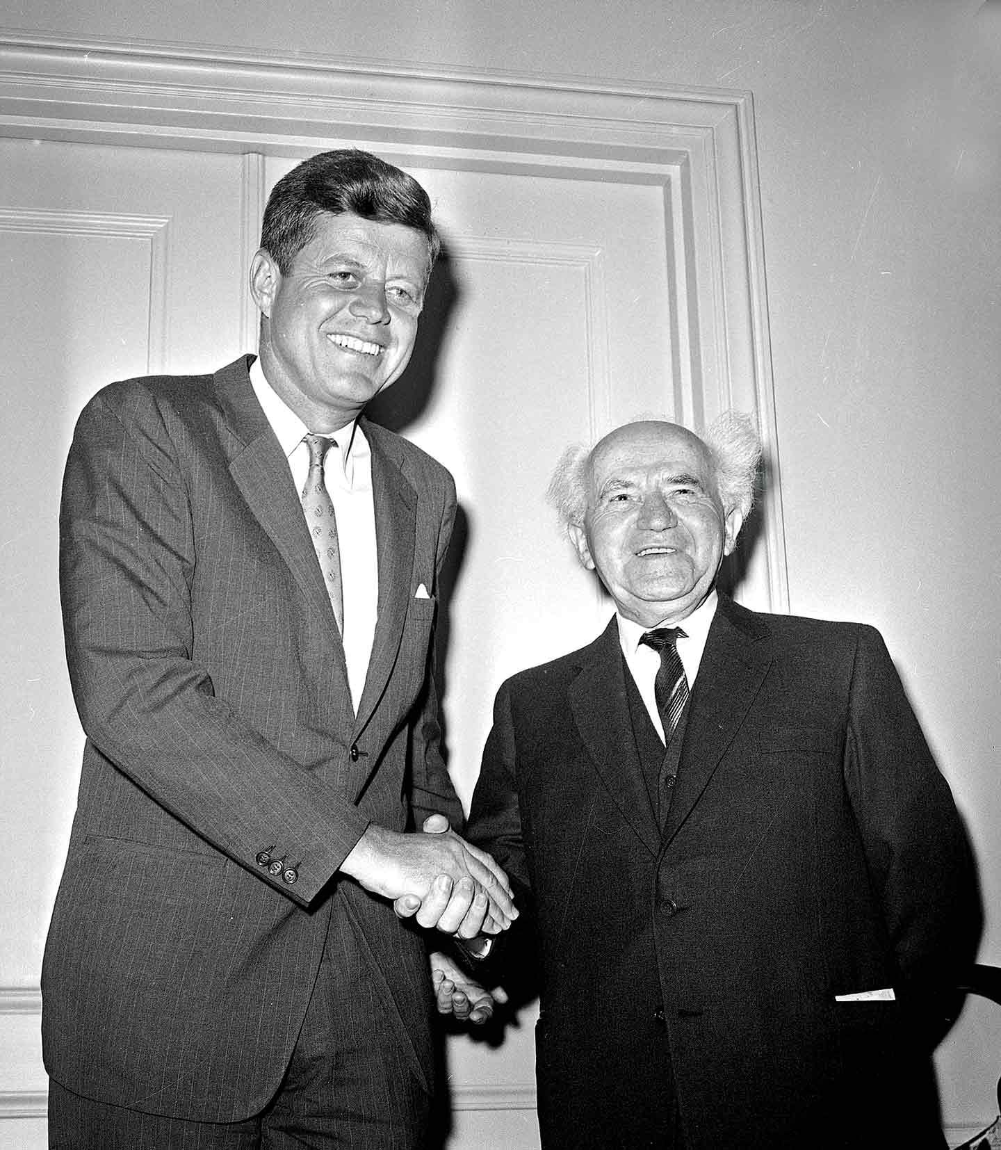 A person in suit shaking hands with another person in suit
Description automatically generated
