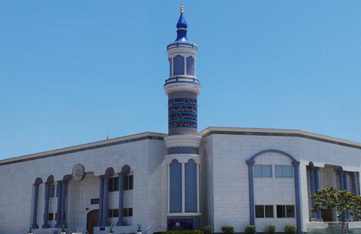 A white building with a blue and white tower

Description automatically generated