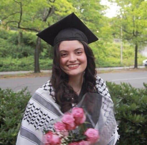 Aysenur Eygi wearing a black mortarboard and holding a bouquet of flowers.