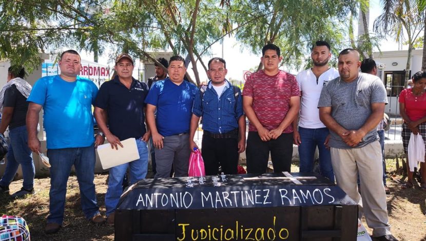 A group of men standing in front of a black rectangular object

Description automatically generated