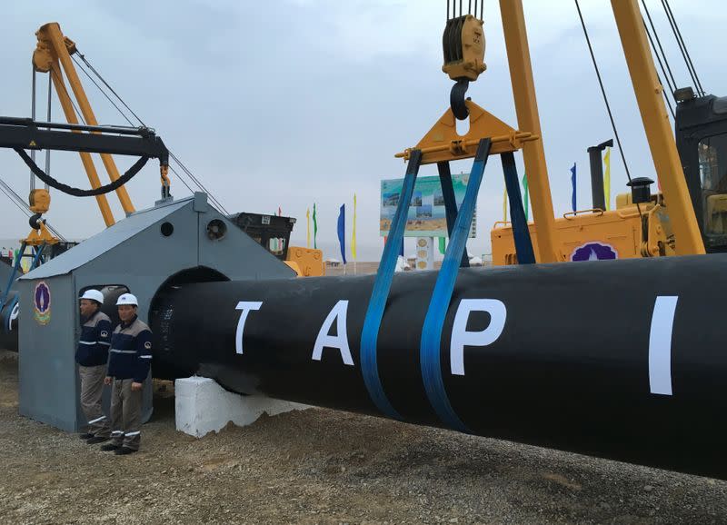 A group of men standing next to a large pipe

Description automatically generated