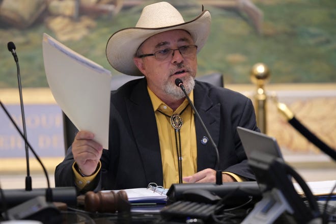 A person in a cowboy hat holding a paper
Description automatically generated