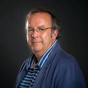 A person wearing glasses and a blue jacket

Description automatically generated