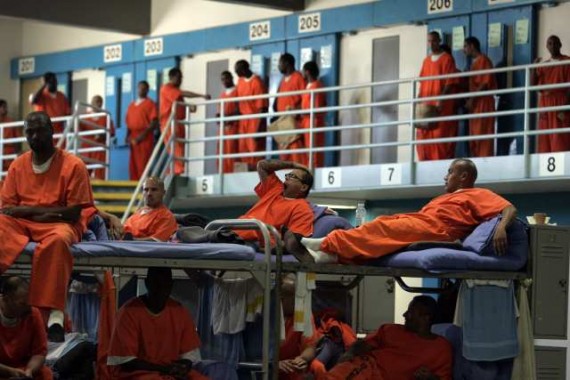 Several men in orange uniforms in a prison

Description automatically generated