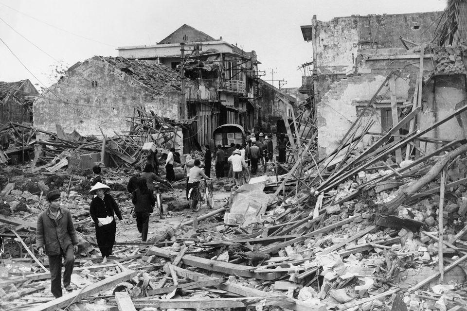 A group of people walking in a destroyed city

Description automatically generated