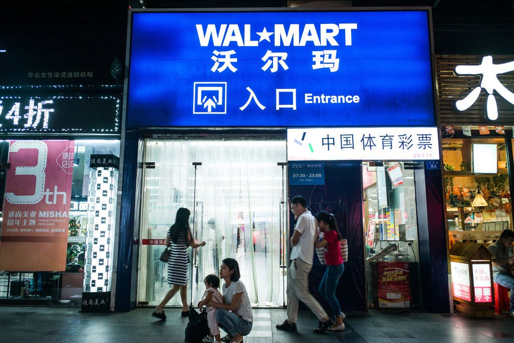 A group of people walking in front of a store

Description automatically generated