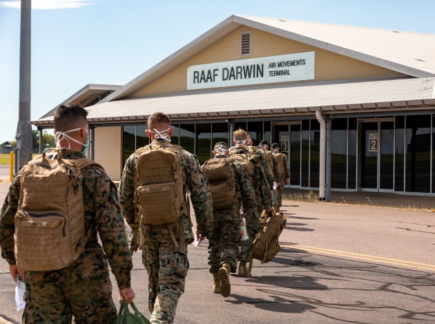 A group of soldiers walking towards a building

Description automatically generated