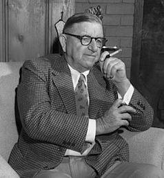 A person in a suit and tie holding a cigarette

Description automatically generated