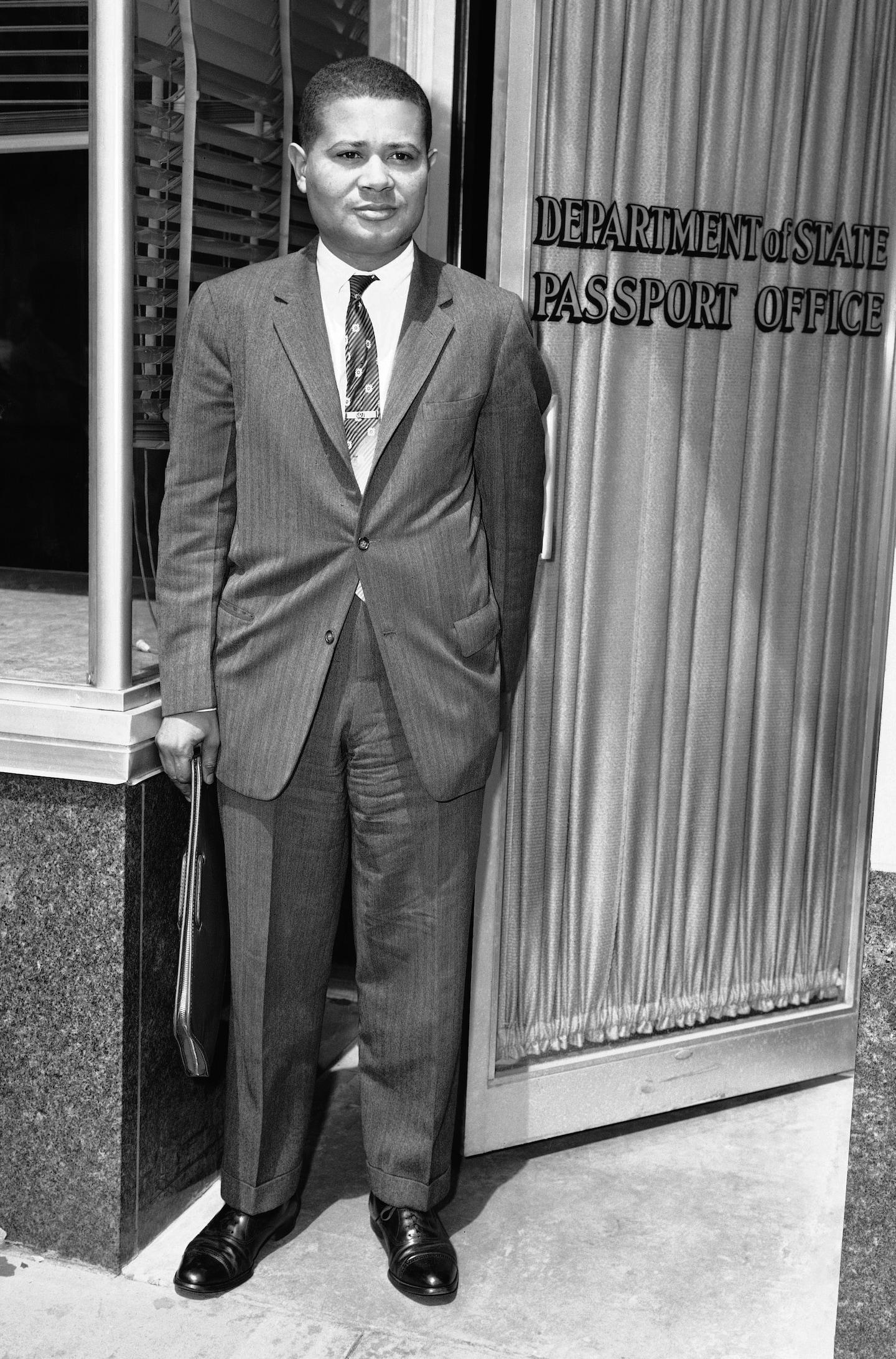 A person in a suit standing in front of a door

Description automatically generated