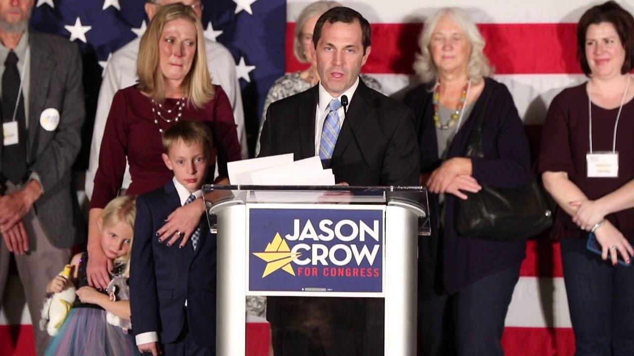 A person standing at a podium with a group of people behind him

Description automatically generated