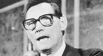A person wearing glasses and a suit

Description automatically generated