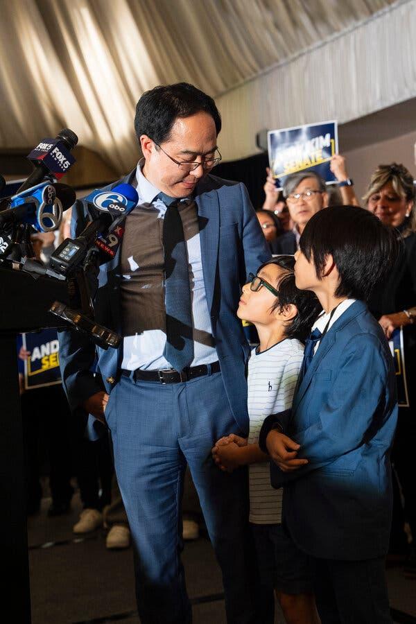 Mr. Kim in a blue suit gazes down at his children during an election night celebration. 