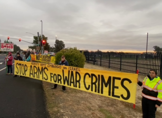 Peace Activists Try and Block Arms Supplies to Israel A group of people holding a yellow banner Description automatically generated