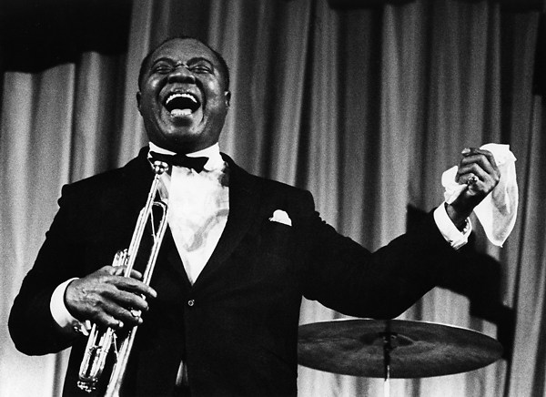 A person holding a trumpet and holding a drum

Description automatically generated
