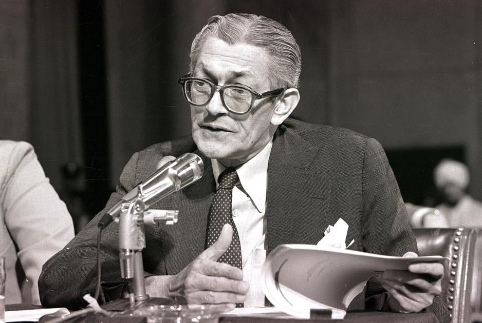 A person in a suit and tie speaking into a microphone

Description automatically generated