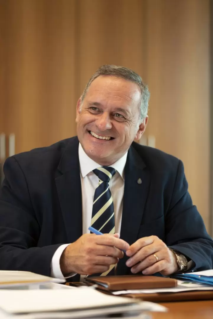 A person in a suit smiling

Description automatically generated
