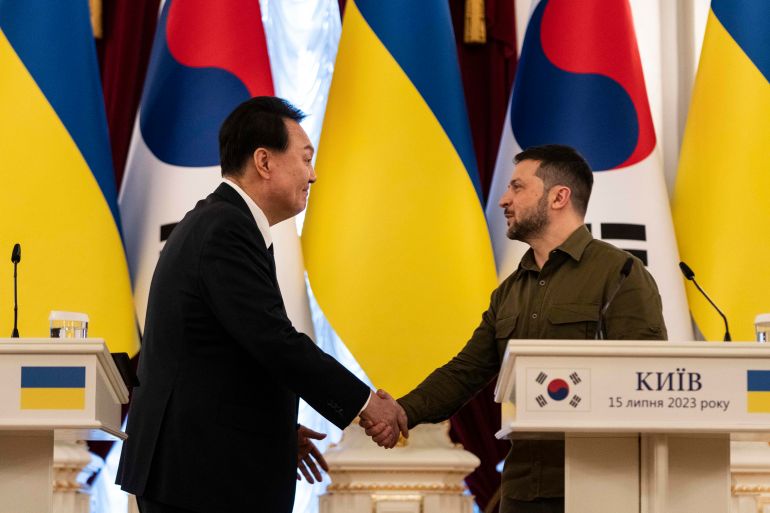 A person shaking hands with another person in front of flags

Description automatically generated