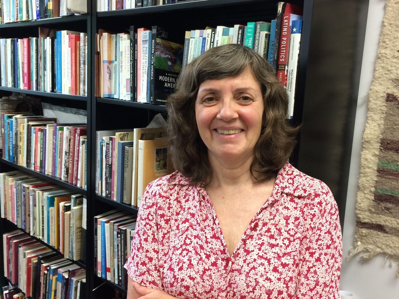 A person standing in front of a bookshelf

Description automatically generated