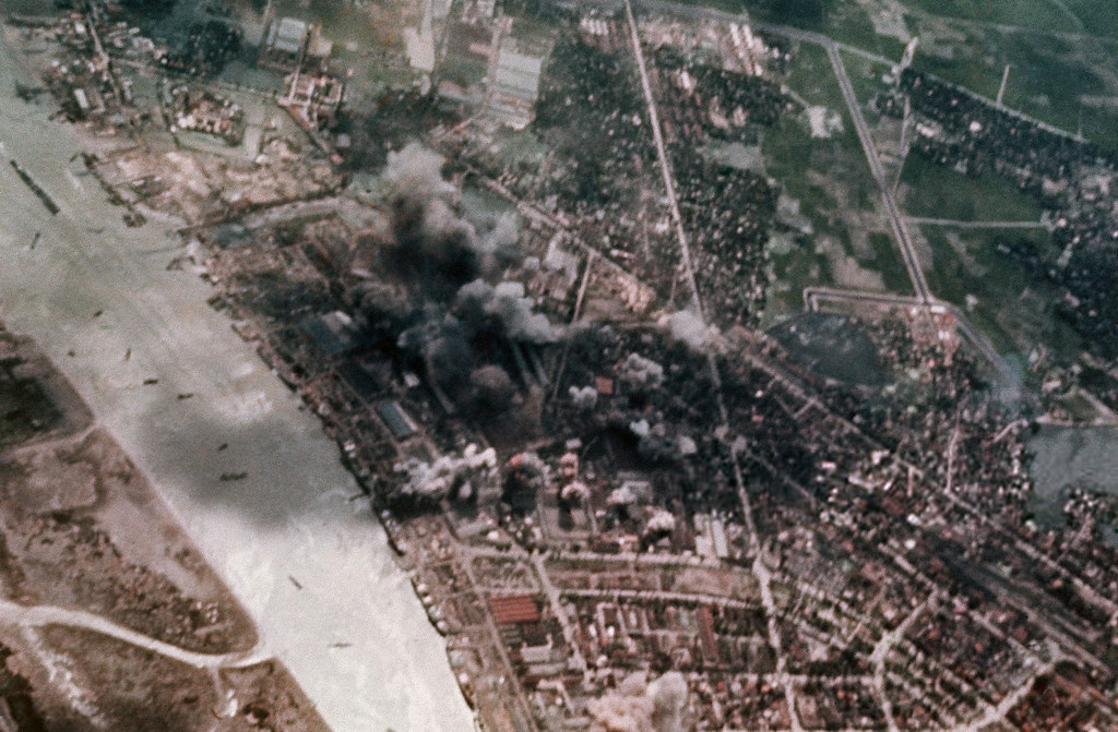 Aerial view of a city with smoke coming out of it

Description automatically generated