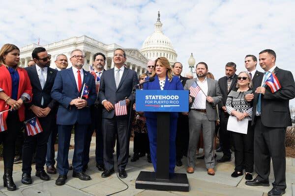 Jenniffer González-Colón standing in front of a podium, which has a sign that reads "Statehood for Puerto Rico."