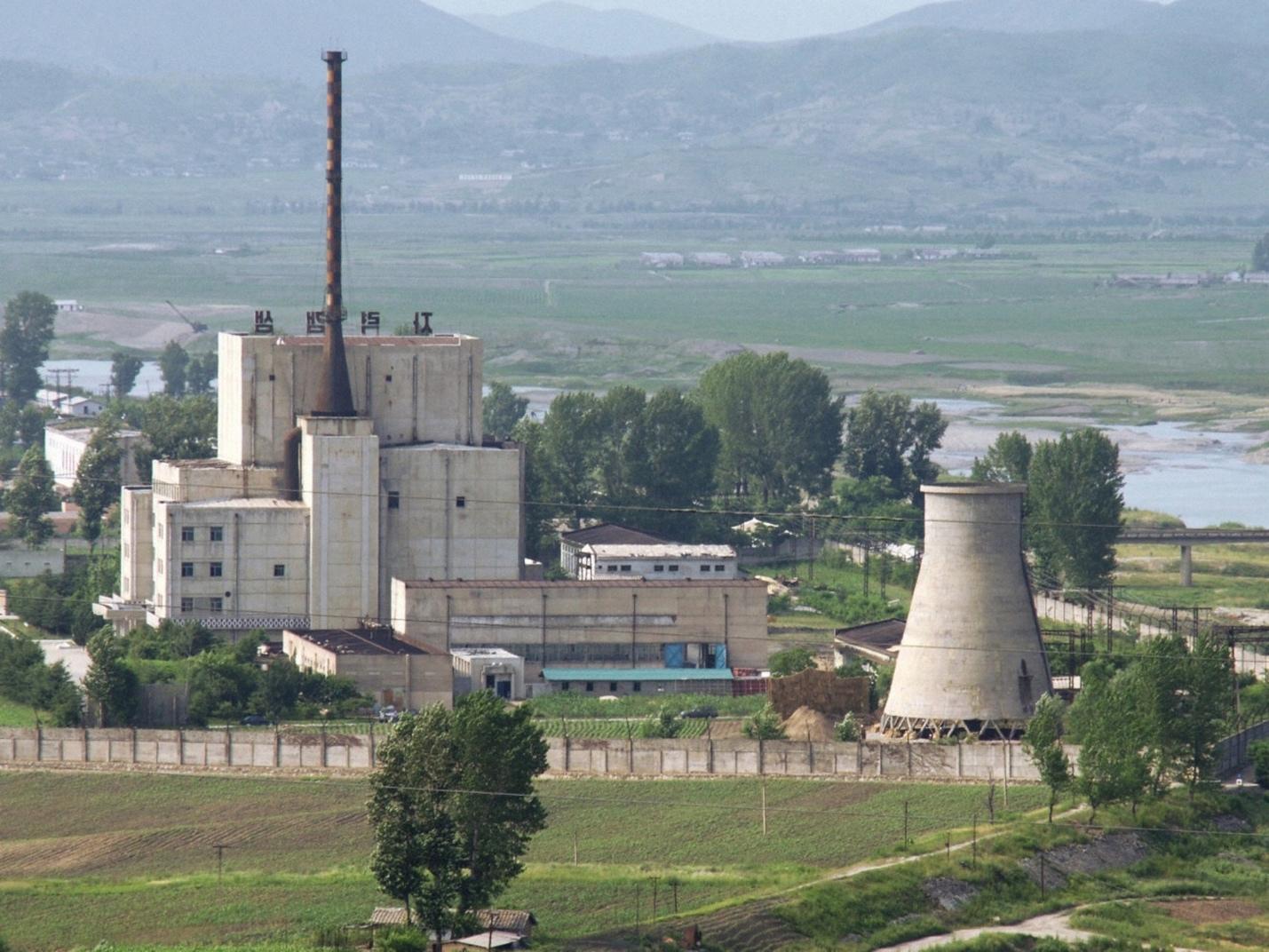 A factory with a chimney and a factory in the background

Description automatically generated