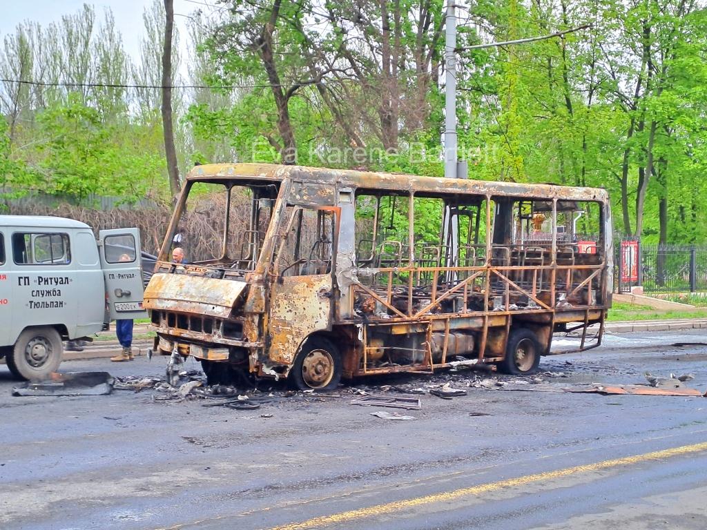 A burnt out bus on the road
Description automatically generated