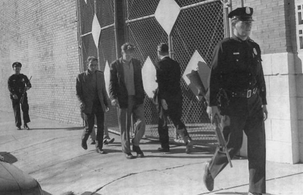 A group of men walking down a sidewalk Description automatically generated