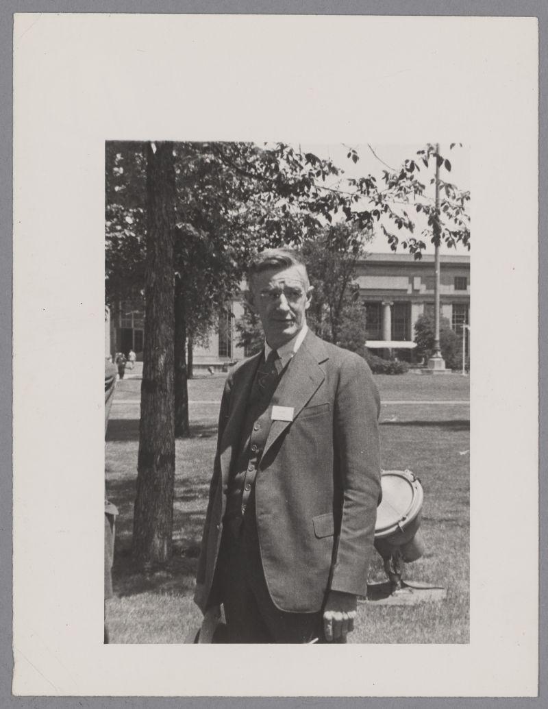 A person in a suit standing outside
Description automatically generated